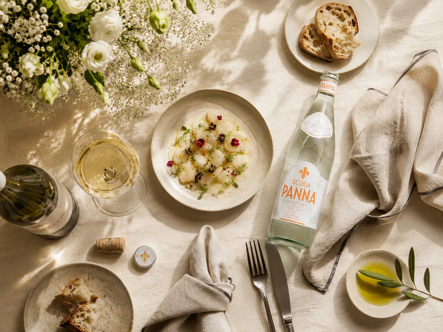 Nước kho&aacute;ng Acqua Panna tr&ecirc;n b&agrave;n ăn fine dining c&ugrave;ng rượu vang v&agrave; m&oacute;n khai vị